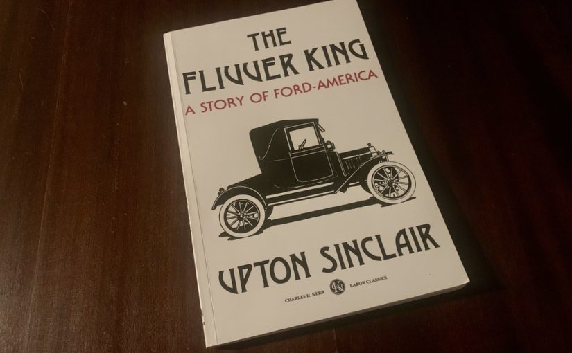 A paperback copy of The Flivver King on a dark wooden table.